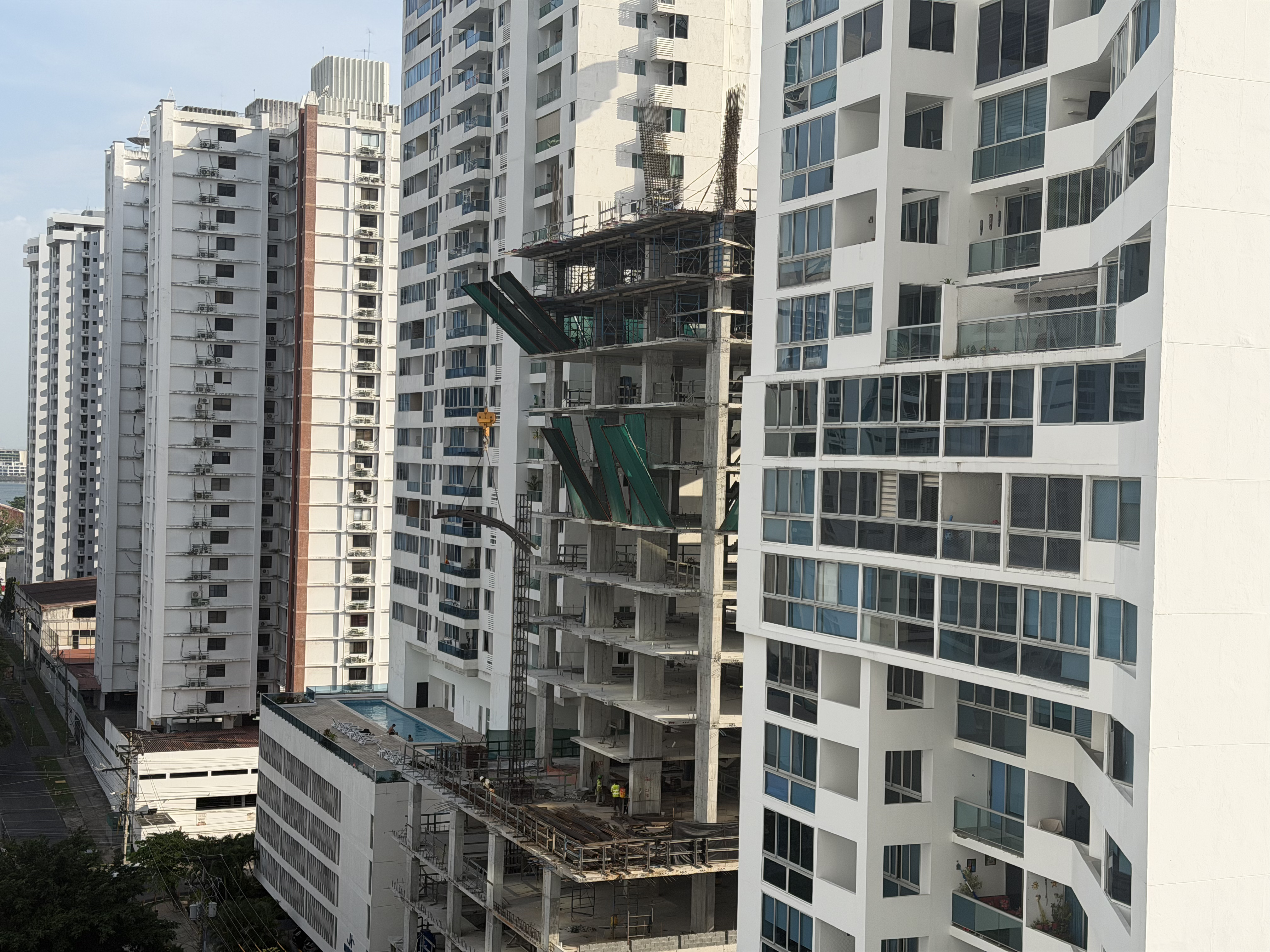 A tower under construction beside an established residential building in Panama, illustrating the risk difference between pre-construction and existing stock